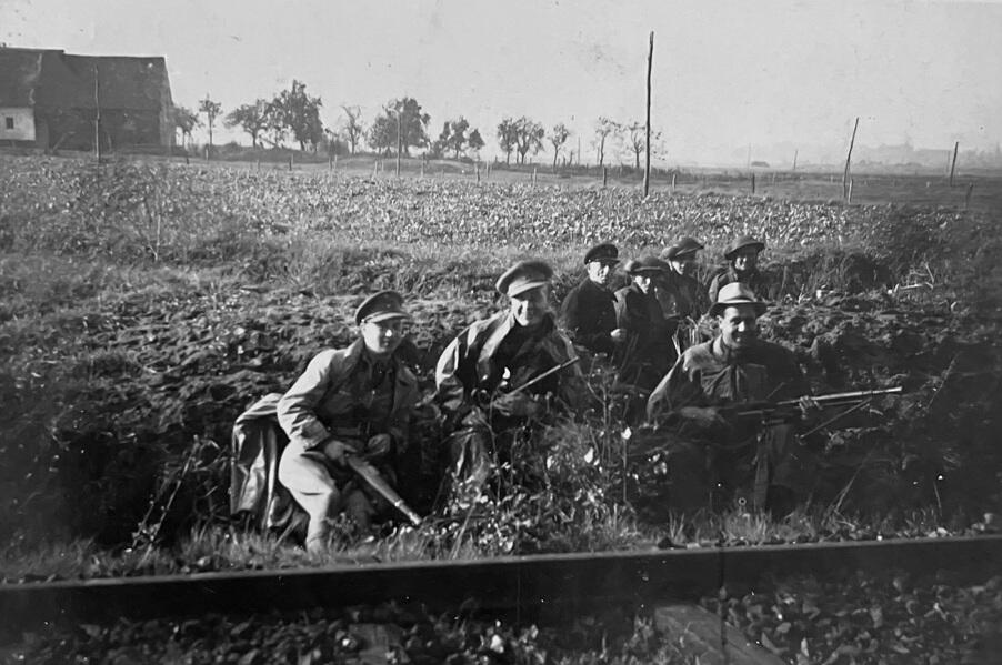 Mensen met wapens gehurkt op een veld