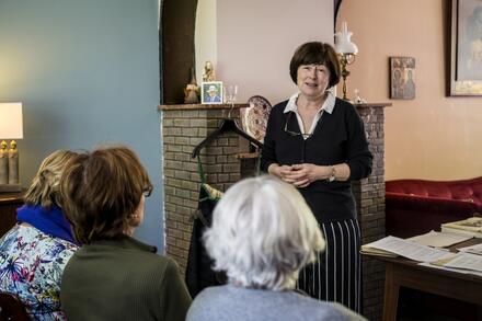 vrouw staat voor zittende mensen