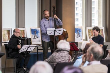 man met accordeon, man met contrabas, zittende mensen