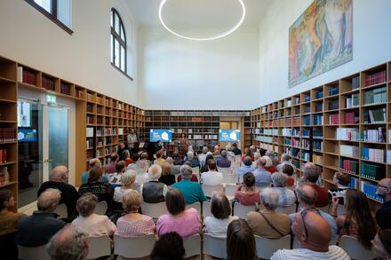 Mensen in zaal met boekenrekken tegen de wanden