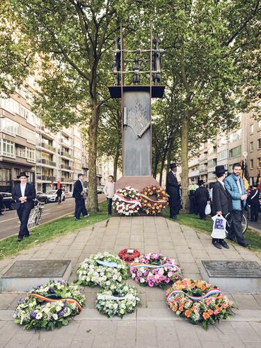 Monument omringd door bloemenkransen en enkele mensen