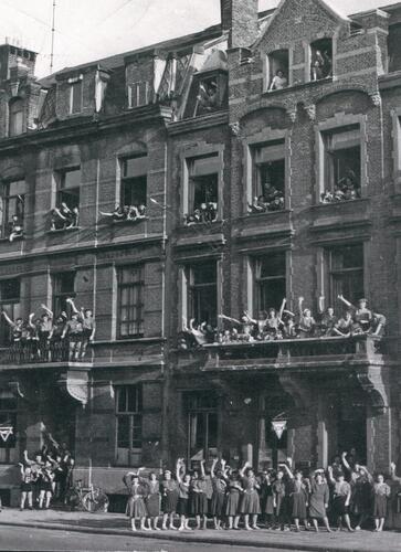 vrouwen op de stoep, op balkons en hangend uit ramen