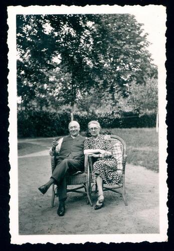 Man en vrouw poseren zittend in tuin.