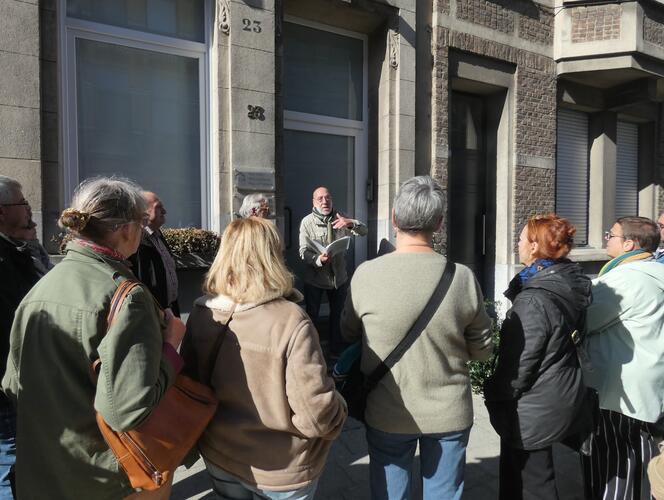 Mensen luisteren naar vertellende man voor een gevel
