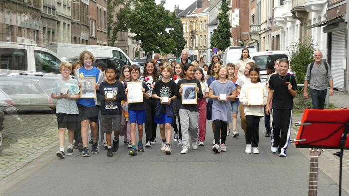 Kinderen wandelen met portretten en stenen over straat