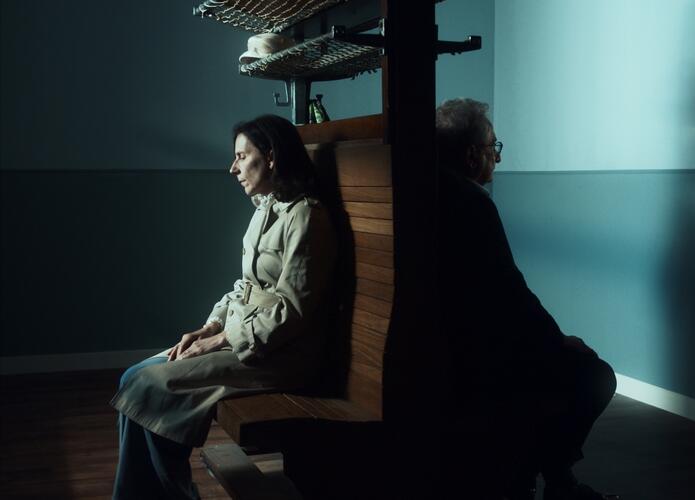 Twee personen op houten banken, de ruggen tegen elkaar