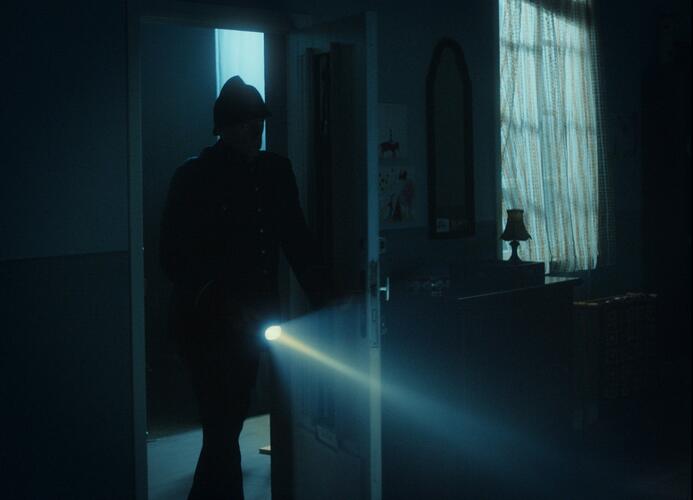 Silhouet met zaklamp wandelt door deur
